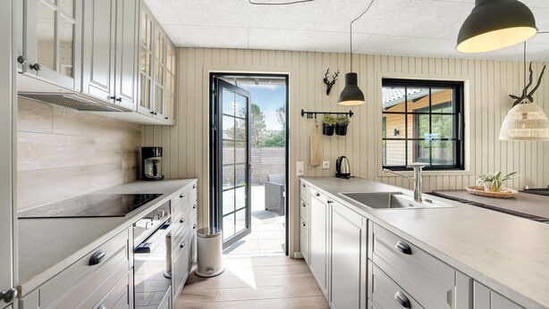 Een moderne keuken met lichte houten kastjes, een groot raam en uitzicht op de omgeving.
