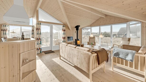 Una habitación amplia con un gran ventanal, un sofá, una mesa y una chimenea.