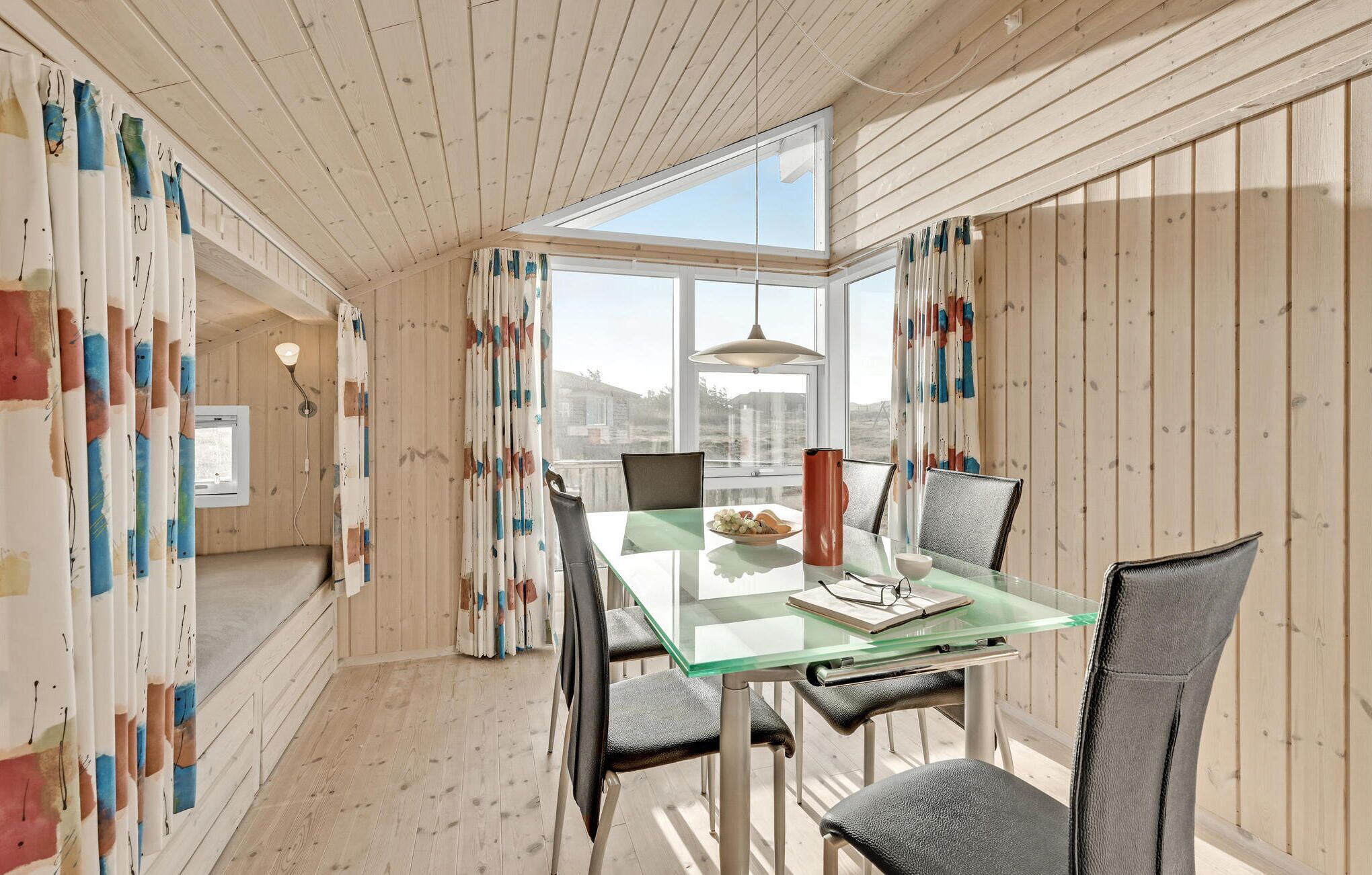 A dining area with a glass table, chairs, and a view of the city through large windows.