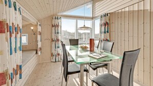 Un comedor con una mesa de vidrio, sillas y vistas de la ciudad a través de amplios ventanales.
