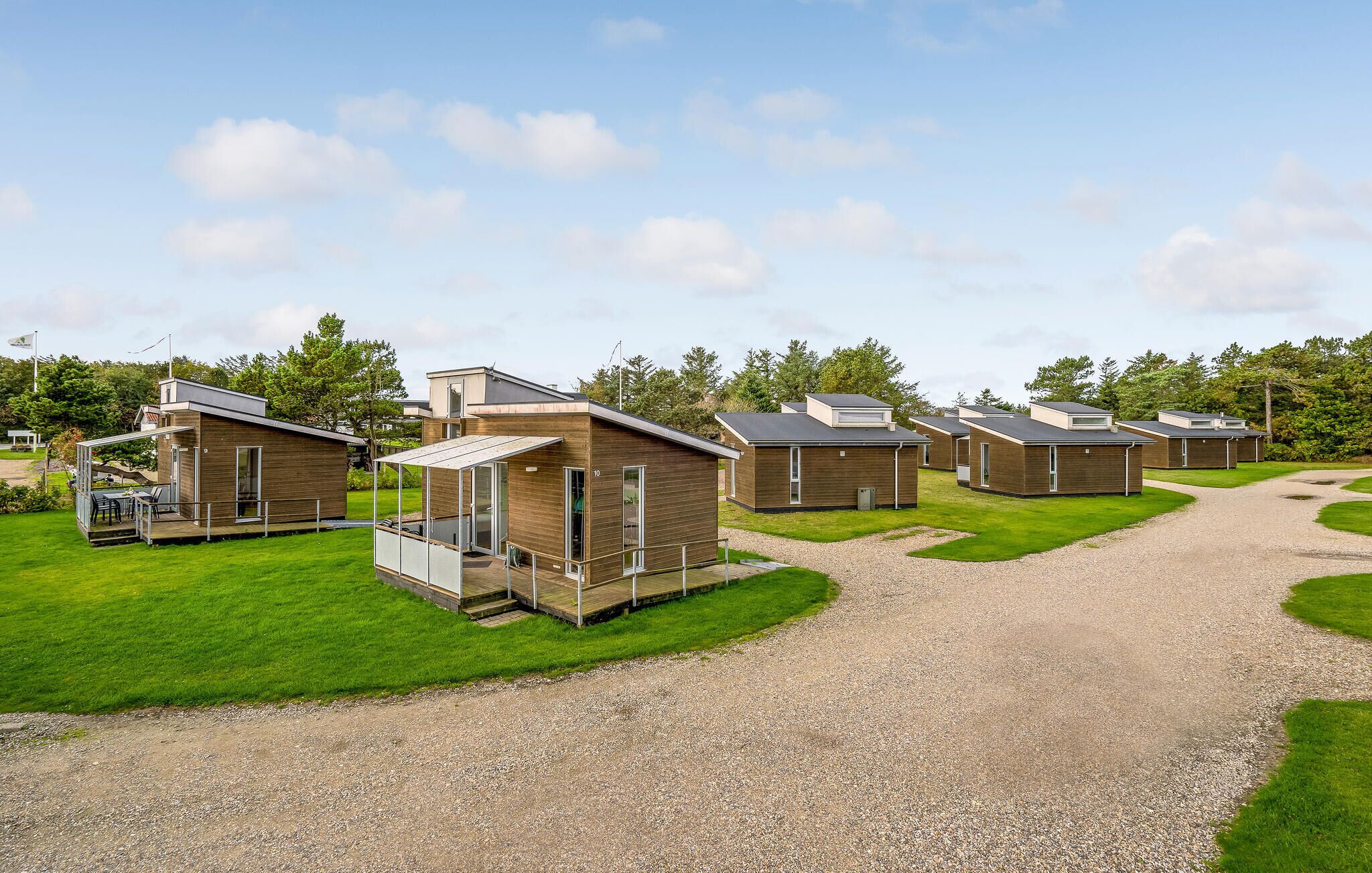 Une rangée de chalets modernes, de plain-pied, avec un chemin de gravier qui traverse la propriété.