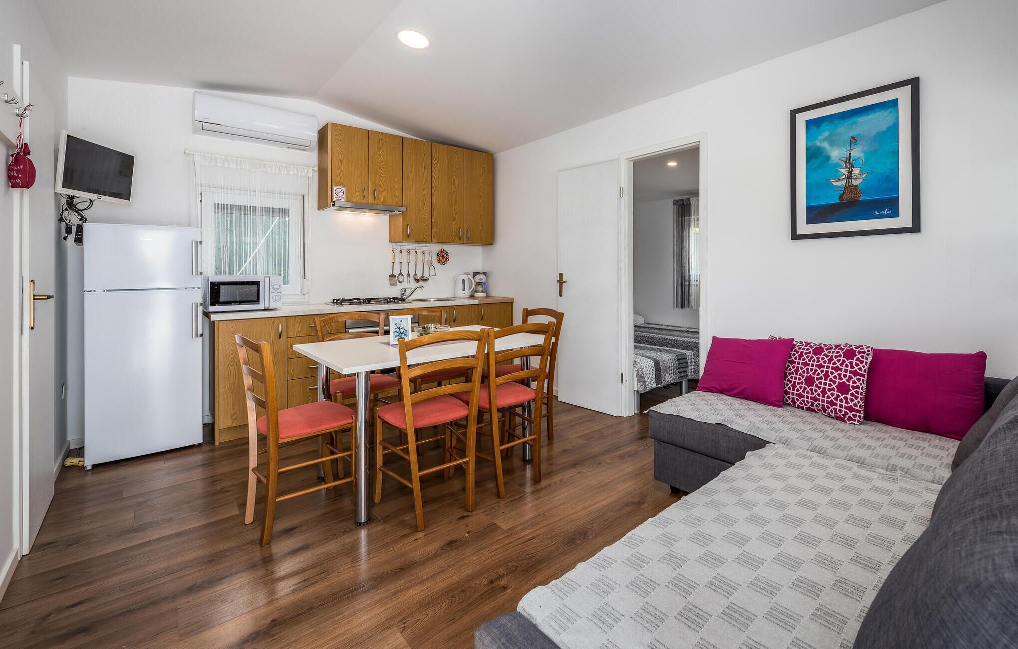 Un espacio habitable compacto con kitchenette, comedor y cama con manta estampada.