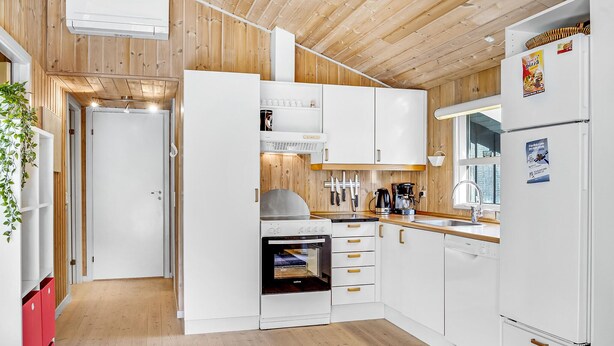 A modern kitchen with white cabinets, a built-in oven, and a refrigerator.