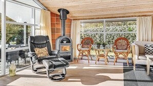 A modern living room with a fireplace, comfortable seating, and large windows offering a view of the outdoors.