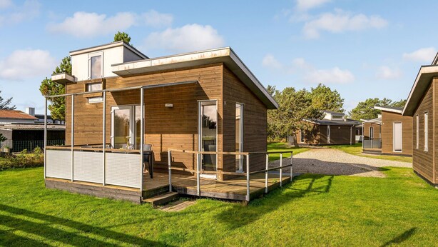 En modern, tvåvånings timmerstuga med en veranda och en täckt uteplats.