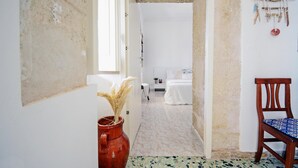 A hallway leading to a bedroom with a bed, a chair, and a rustic decor wall. - Lovely home in Cava D'aliga with house sea view (Cava D'aliga)