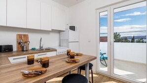 Cuina moderna amb armaris blancs, tauleig de fusta i vista a l'exterior a través d'una porta corredissa de vidre.