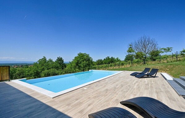 Relax by the pool surrounded by lush greenery and comfortable lounge chairs.