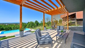 Un espacio al aire libre techado con piscina, sillas y una mesa.