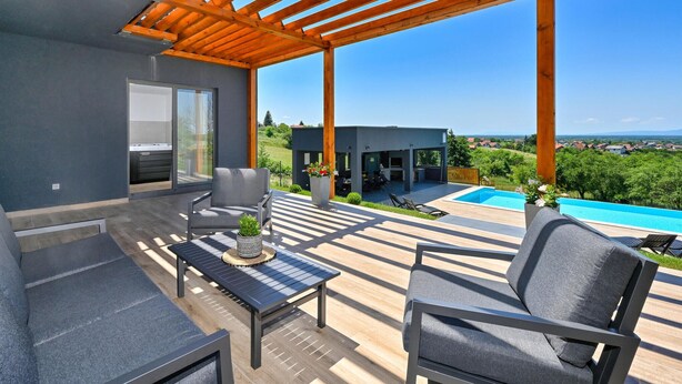 Un patio moderno al aire libre con piscina, mobiliario y vistas al paisaje.
