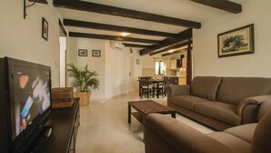 A living room with a television, a sofa, a coffee table, and a dining area with chairs and a table. - Stunning home in Labin (Labin)