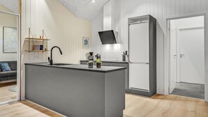 Una cocina moderna con una isla central, un horno integrado y un televisor de pantalla plana sobre el horno.