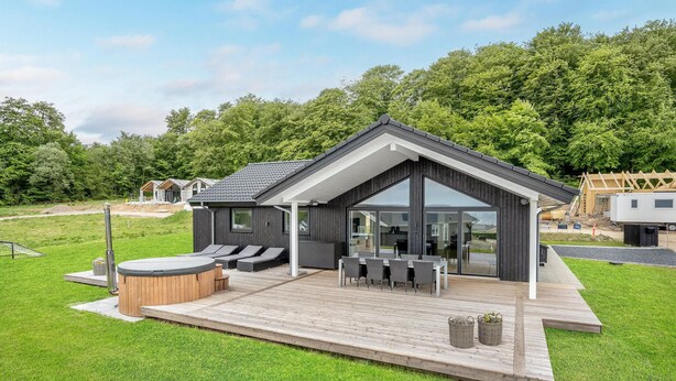 Una casa moderna con una amplia terraza, mobiliario exterior y un jacuzzi.