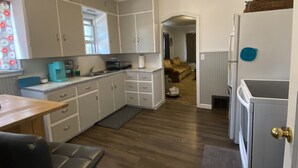 Une cuisine de taille réduite avec des meubles blancs, un plan de travail en bois et un réfrigérateur.