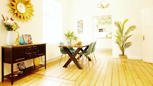 A dining area with a wooden table and chairs, a decorative sun on the wall, and a potted plant. - ARTstudio 2.0 Superior 2-bedroom apartment with terrace. Near IGA 27! (Duisburg)