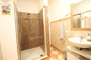 Une salle de bain avec une douche, un lavabo et un miroir.