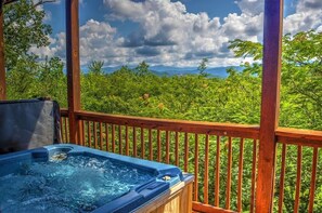 A hot tub on a wooden deck with a view of a lush green landscape and mountains in the distance. - Don't be shy...Visit the mountains! Amazing Views, King Bedrooms, Secluded. (Sevierville)