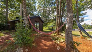 A rustic cabin with a hammock in a forested area.
