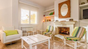 A living room with a white sofa, striped armchairs, a white coffee table, a fireplace, and a bookshelf. - Awesome home in Alacant with WiFi (Alacant)