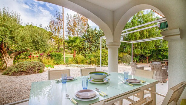An outdoor dining area with a table set for four, surrounded by white columns and wicker furniture. - Awesome home in Alacant with WiFi (Alacant)