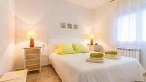 A neatly arranged bedroom with a bed, two bedside tables with lamps, a radiator, and a window with curtains. - Awesome home in Alacant with WiFi (Alacant)