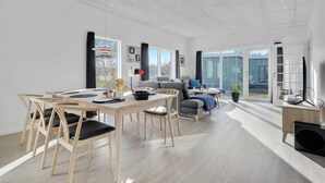 Ein modernes Wohnzimmer mit Essbereich, großen Fenstern und Blick ins Freie.