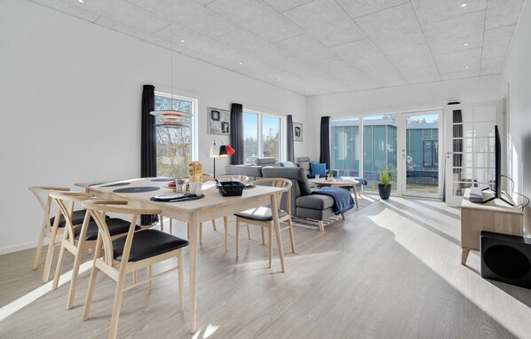 Relax in this stylish living space with a dining area, comfortable sofa, and large window offering a view of the outdoors.