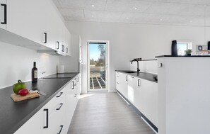 Prepare meals in a modern kitchen with a sleek countertop, white cabinetry, and a large window offering a view of the outdoors.