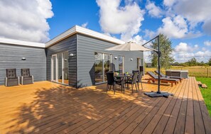 Relax on the spacious deck with comfortable seating and a hot tub nearby.