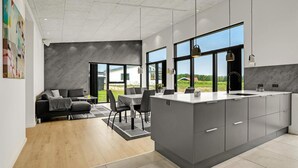 A modern kitchen with a large island, dark cabinetry, and a view of the outdoors. - Gorgeous home in Sjølund with kitchen (Sjølund)