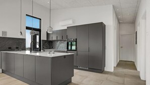 A modern kitchen with a central island, dark cabinetry, and a view to the outside. - Gorgeous home in Sjølund with kitchen (Sjølund)