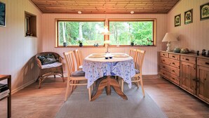 A dining area with a round table, chairs, a rug, a window with a view of trees, and a wooden cabinet. - Cozy home in Perstorp with WiFi (Perstorp)