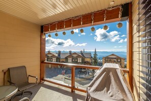 Balkon med udsigt over huse og bjerge, en stol og et overdækket bord.
