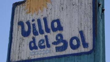 Un letrero desgastado con el texto 'Villa del Sol' sobre un fondo azul y blanco.