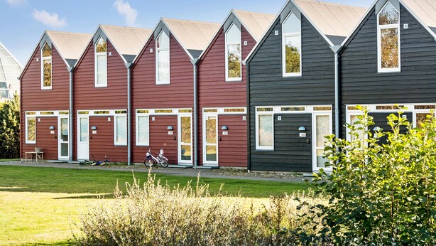 Uma fileira de casas modernas, com dois andares, telhados empenaados e grandes janelas.