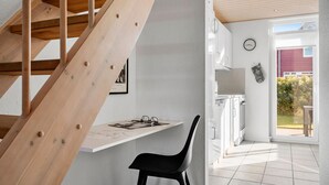 Cozinha moderna com armários brancos, escada de madeira e vista para o exterior.