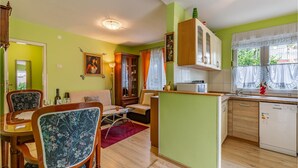 A compact kitchen with a dining area, a sofa, and a cabinet with a microwave. - 1 bedroom beach front apartment in Premantura (Premantura)