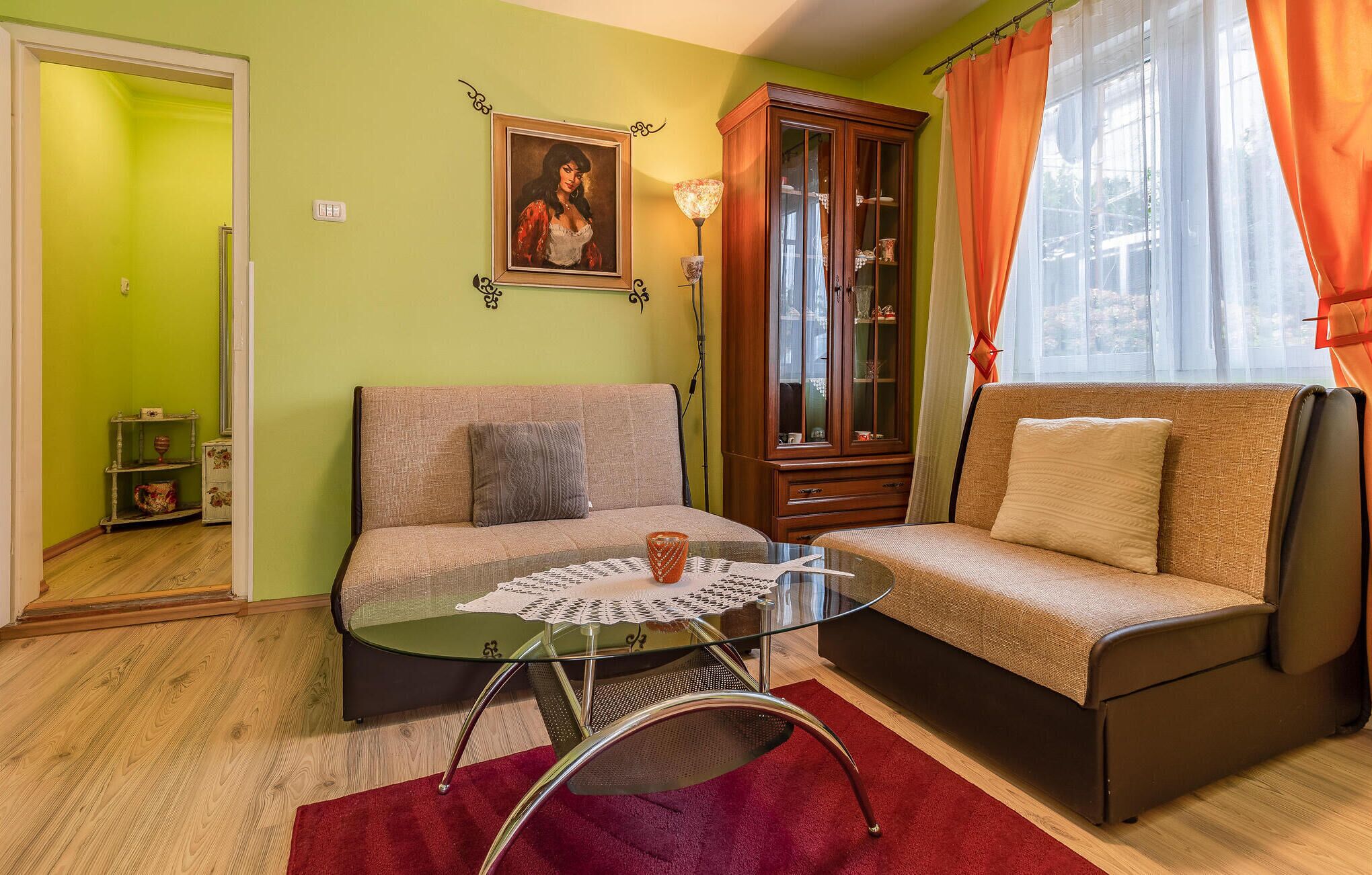 A living room with a sofa, a glass coffee table, a cabinet, and a painting on the wall.