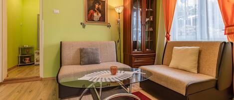 A living room with a sofa, a glass coffee table, a cabinet, and a painting on the wall.