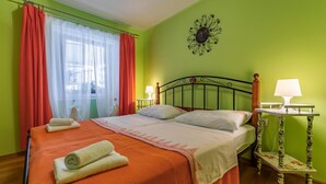 A room with a bed, two bedside tables with lamps, a window with curtains, and a wall decoration. - 1 bedroom beach front apartment in Premantura (Premantura)