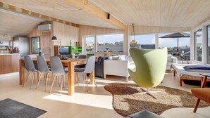 A modern living room with a dining area, large windows, and a view of the cityscape. - 4 bedroom cozy home in Rønde (Rønde)
