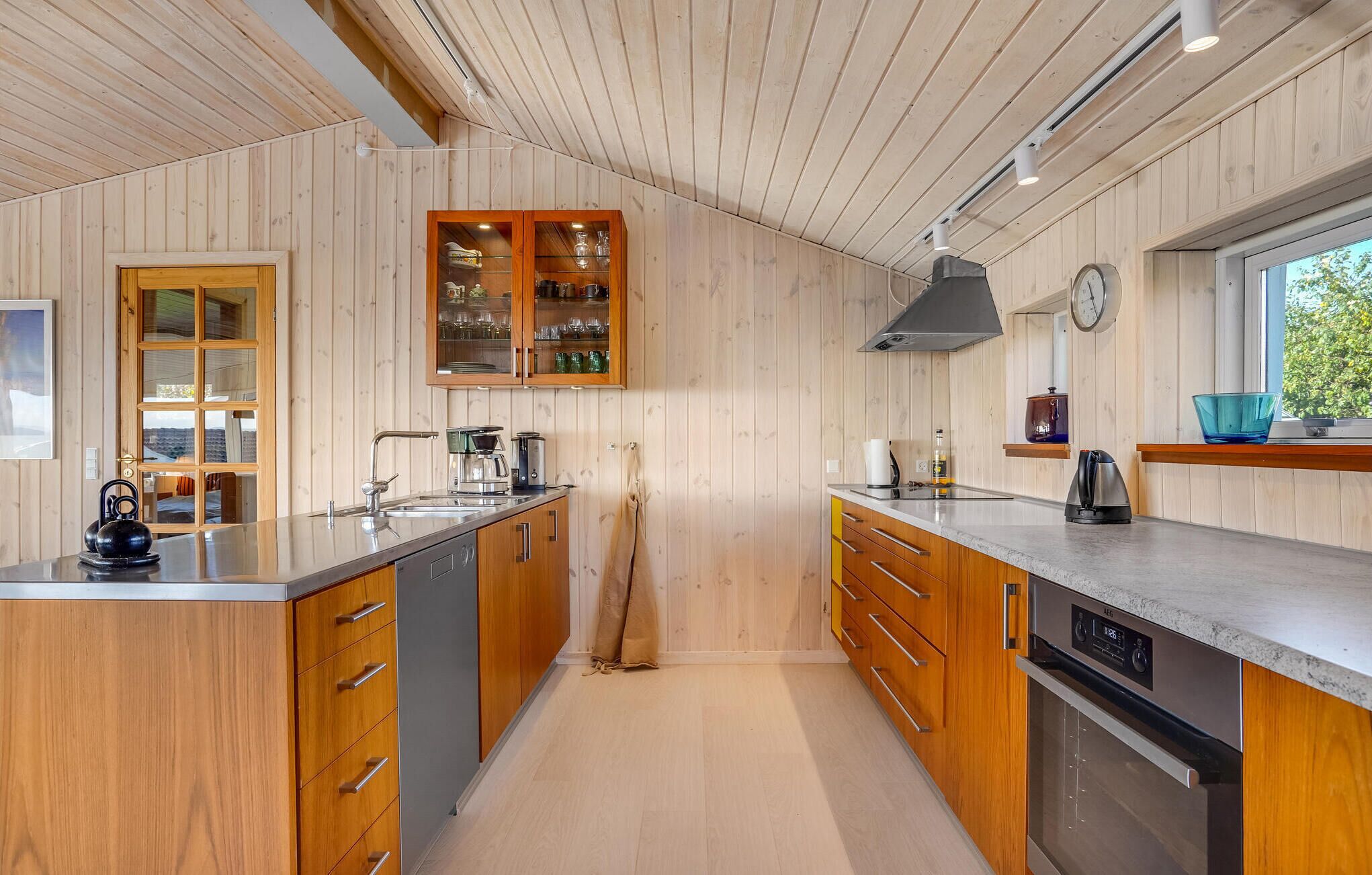 A modern kitchen with wooden cabinetry, a central island, and a built-in oven.