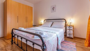 A bedroom with a bed, wooden wardrobe, bedside tables, and a wall clock.