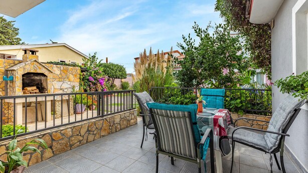 A patio with stone walls, a stone fireplace, and outdoor furniture.