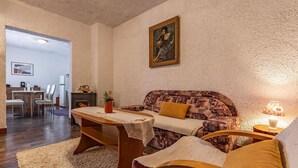 A cozy living room with a sofa, a dining table, and a painting on the wall.