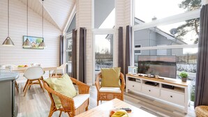 A cozy living room with wicker furniture, a large TV, and a view of a snowy landscape. - Amazing home in Krems II/Warderbrück with sauna (Krems II/Warderbrück)