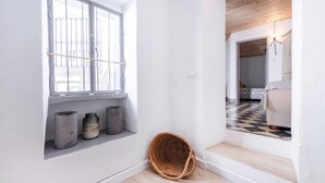 A hallway with a large window, a wicker basket, and a checkered floor.