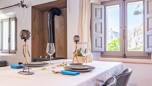 A dining table set with plates, glasses, and cutlery, with a wooden interior and large windows.