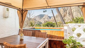 An outdoor patio with a pool, wooden furniture, and a view of mountains.