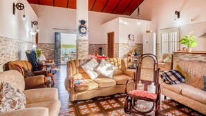 A spacious living room with wicker furniture, a red ceiling, and a view to an outdoor area. - Beautiful home in Alcolea del Rio (Alcolea del Rio)
